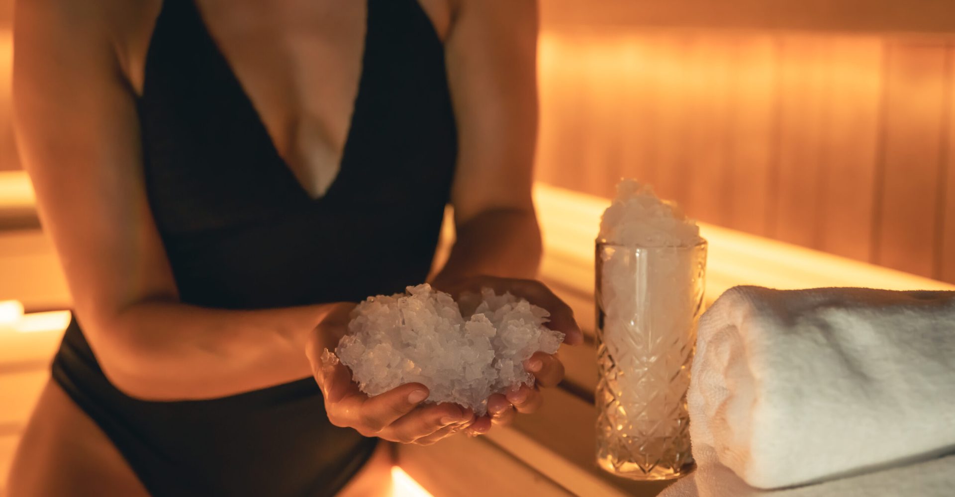 Woman in a sauna with ice in a glass, close-up.